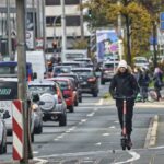 Mann fährt E Scooter im Straßenverkehr