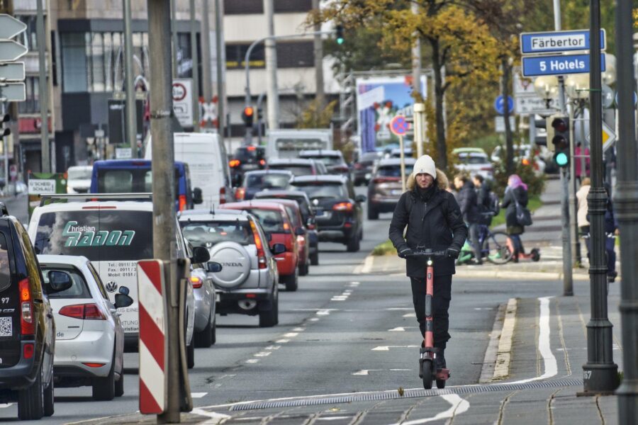 Mann fährt E Scooter im Straßenverkehr